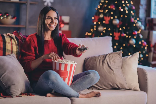 Photo of young happy beautiful smiling cheerful woman eat popcorn watch tv use controller sit sofa at home house — Stock Photo, Image