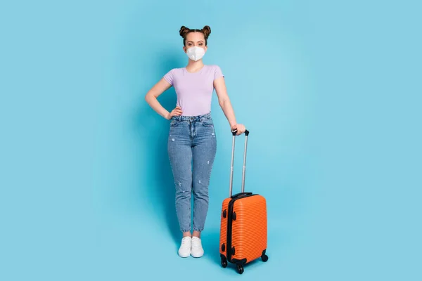 Foto de longitud completa de señora atractiva viajero uso respirador esperar registro del aeropuerto caso de rodaje volar a casa ver a los padres verano usar camiseta jeans zapatos aislados color azul fondo —  Fotos de Stock