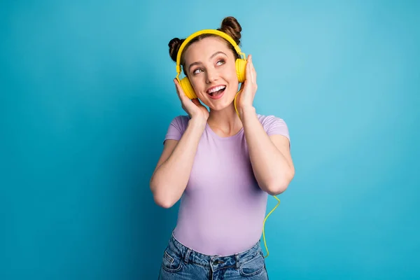 Bild av attraktiv galen dam två roliga bullar gott humör lyssna modern teknik hörlurar sjunga populär låt slå upp tomt utrymme slitage casual lila t-shirt isolerad blå färg bakgrund — Stockfoto