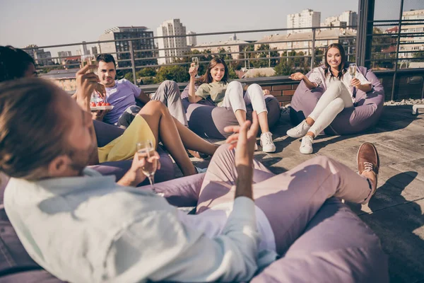 Foto av unga leende glada positiva glada glada grupp människor sitter i påse bönor fåtölj dricka vin utanför på taket — Stockfoto