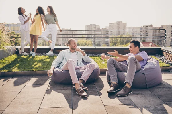 Foto av två unga glada leende glada positiva män sitta fåtölj dricka champagne prata kommunicera utanför på taket — Stockfoto