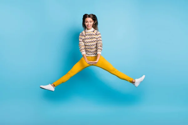 全长照片，滑稽的年轻女士穿着华丽的饰物毛衣跳跃腿两侧孤立的蓝色背景 — 图库照片