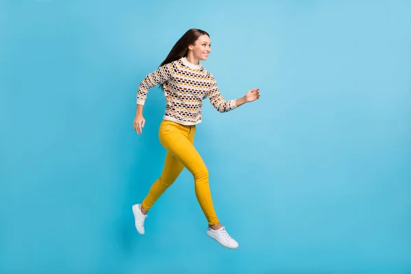 Pełna długość zdjęcie celowe młoda kobieta ubrana ozdoba pullover skoki uruchomiony odizolowany niebieski kolor tła — Zdjęcie stockowe