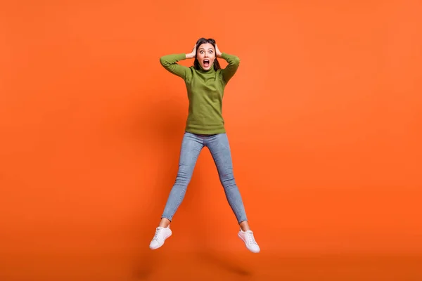 Foto de larga duración de la joven sorprendida asustado pánico noticias salto manos toque la cabeza aislado sobre fondo de color naranja —  Fotos de Stock