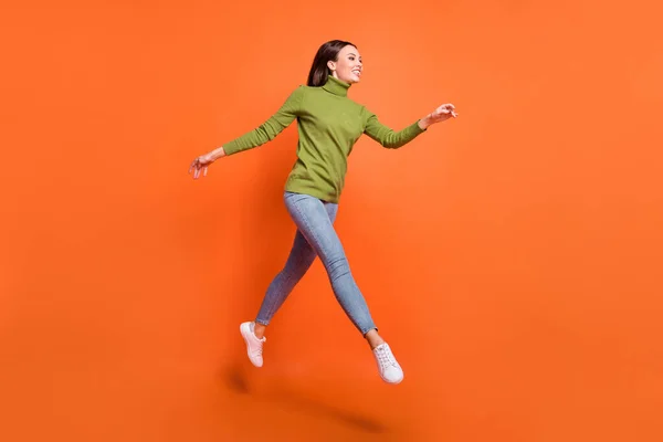 성큼성큼 뛰어다니는 젊은 소녀의 전체 프로필 사진 오렌지 색 배경 위에 격리 된 빈 공간처럼 보인다 — 스톡 사진