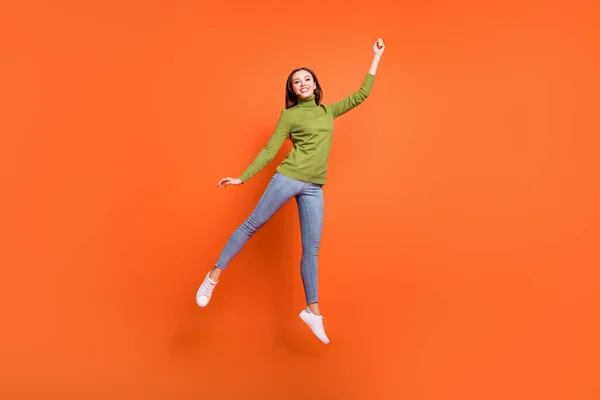 Фотография девушки в полный рост, счастливая позитивная улыбка, сумасшедший прыжок, весело провести время на оранжевом фоне — стоковое фото