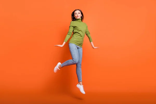 Foto em tamanho completo de jovem atraente menina feliz positivo enviar beijo de ar se divertir salto isolado sobre fundo cor de laranja — Fotografia de Stock