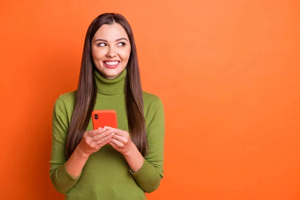 Foto van jong mooi glimlachen vrolijk positief mooi meisje kijken copyspace hold smartphone geïsoleerd op oranje kleur achtergrond — Stockfoto