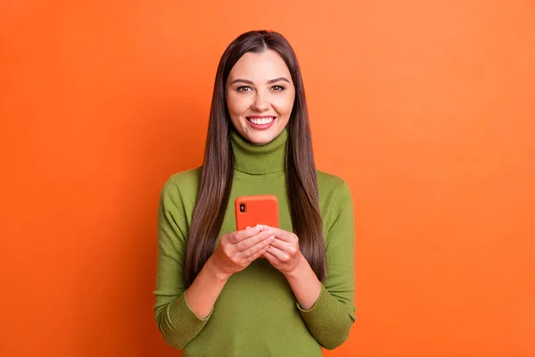 Foto de joven atractiva sonriente chica positiva feliz freelancer mantenga el teléfono inteligente aislado en el fondo de color naranja — Foto de Stock