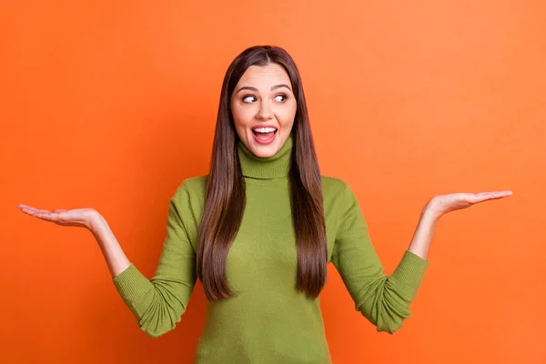 Foto de joven atractiva sonrisa excitada chica bonita mirada copyspace tomarse de la mano en equilibrio aislado sobre fondo de color naranja — Foto de Stock