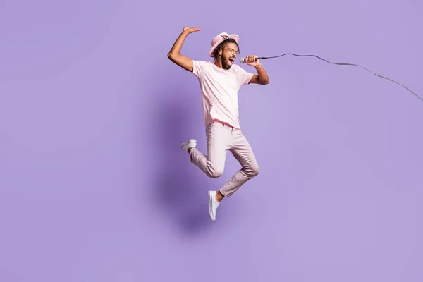 Foto em tamanho completo de jovem afro bonito louco feliz homem animado pular voar cantar no microfone isolado no fundo cor roxa — Fotografia de Stock