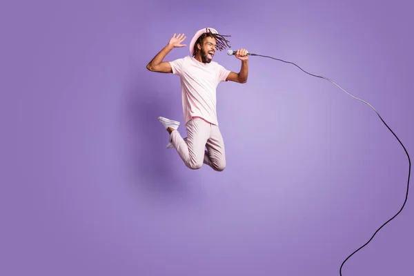 Plná velikost fotografie mladých afro šťastný šílený pozitivní muž chlap skok moucha zpívat v mikrofonu izolované na fialové barvy pozadí — Stock fotografie