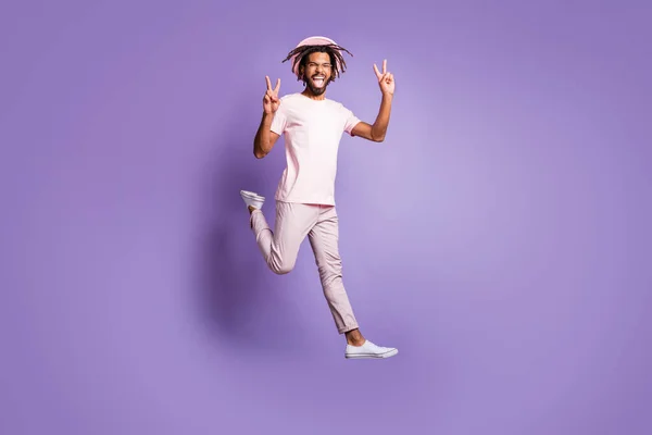 Foto em tamanho completo do jovem africano feliz louco homem animado cara gripe salto mostrando v-sinal isolado no fundo cor violeta — Fotografia de Stock