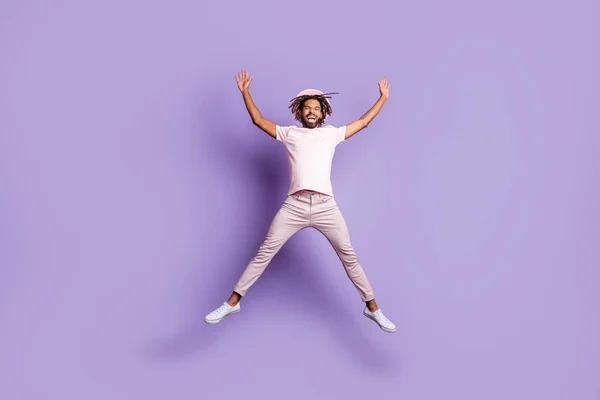 Foto em tamanho completo de jovem afro bonito animado alegre homem homem macho salto voar levantar as mãos isolado no fundo cor violeta — Fotografia de Stock