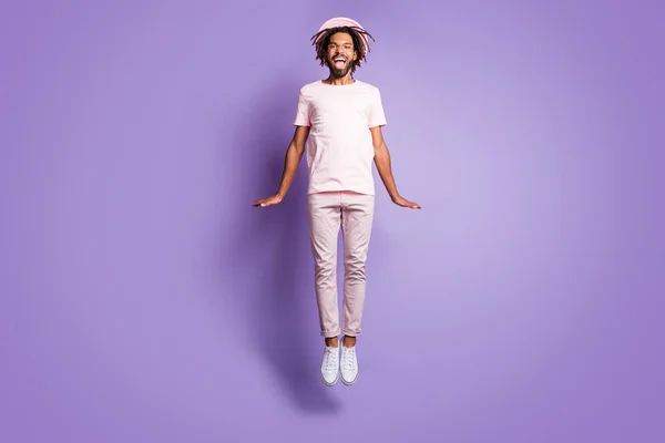 Foto em tamanho completo de jovem afro bonito alegre sorridente homem homem macho salto voar em excitação isolada no fundo cor roxa — Fotografia de Stock