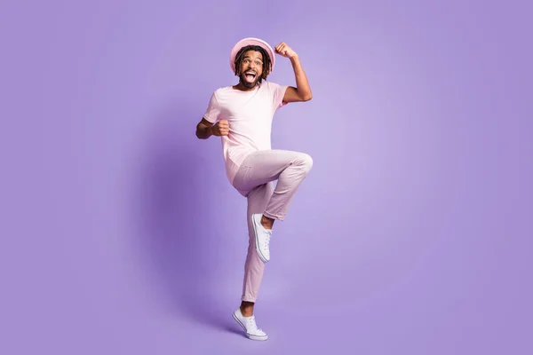 Foto em tamanho completo de jovem afro bonito animado louco homem feliz cara masculino levantar punhos de perna isolado no fundo cor violeta — Fotografia de Stock