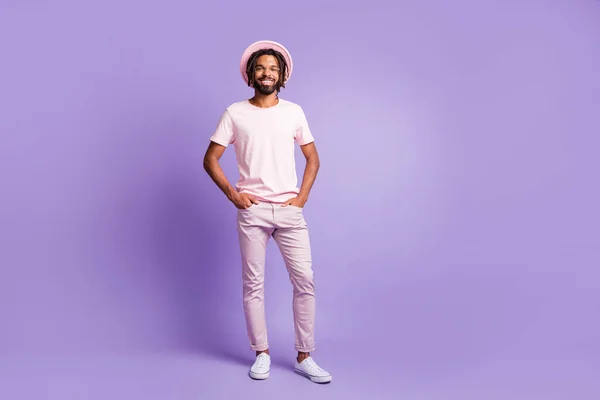 Foto de jovem afro bonito alegre bom humor homem positivo cara masculino posando segurar as mãos em bolsos isolados no fundo cor violeta — Fotografia de Stock