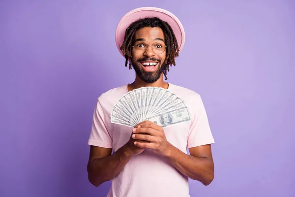Foto mladého afro hezký šťastný úsměv pozitivní muž muž chlap držet peníze dolarů izolovaných na fialové barvy pozadí — Stock fotografie