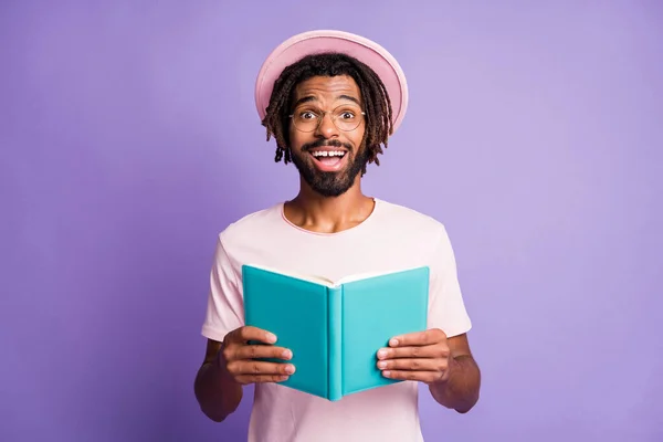 Foto do jovem africano bonito sorrindo alegre homem feliz cara masculino segurar caderno azul isolado no fundo cor roxa — Fotografia de Stock