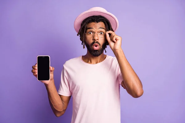 年轻非洲裔男子震惊男性男子的照片演示用紫色背景隔离的手机显示屏触摸镜 — 图库照片