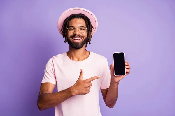 Retrato fotográfico de un tipo con sombreros casuales señalando con el dedo al teléfono con copyspace aislado sobre un fondo de color violeta vivo — Foto de Stock