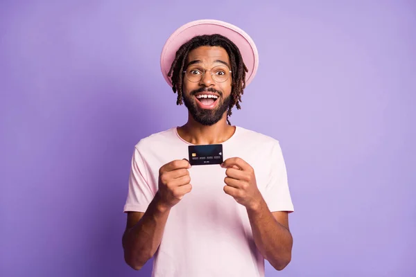 Foto retrato de tipo excitado sosteniendo tarjeta de crédito en dos manos aisladas sobre fondo de color violeta vivo — Foto de Stock