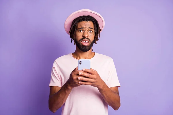 Foto retrato de homem infeliz segurando telefone em duas mãos isoladas em violeta vivo fundo colorido — Fotografia de Stock