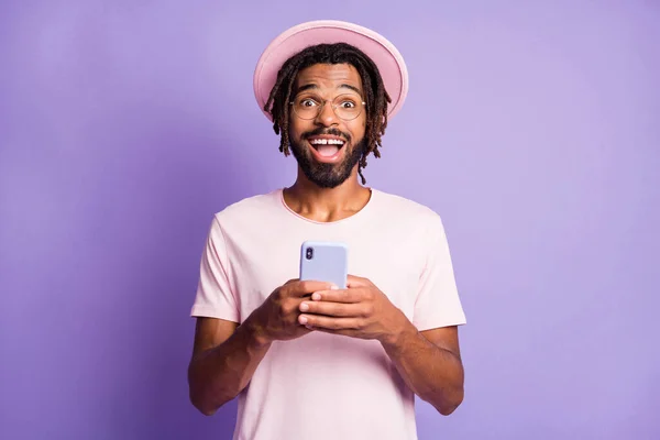 Retrato fotográfico de un hombre excitado en un auricular rosa sosteniendo el teléfono en dos manos aisladas sobre un fondo de color violeta vivo — Foto de Stock