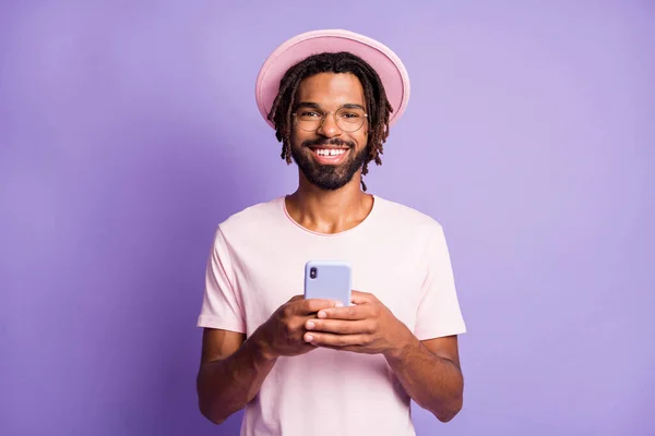 밝은 자주색 배경에 핸드폰을 두 손에 들고 있는 행복 한 남자의 사진 — 스톡 사진