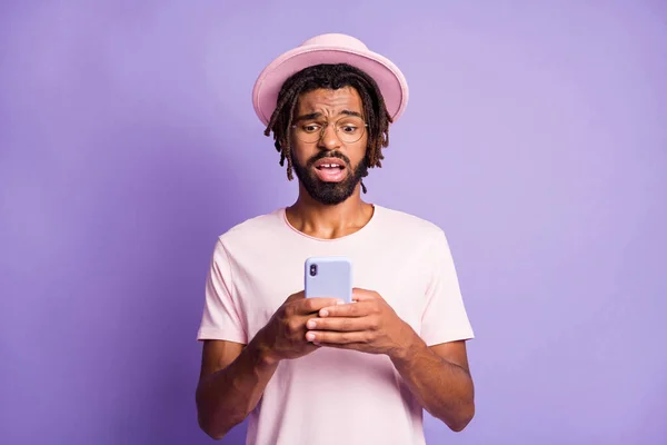 Foto ritratto di ragazzo sconvolto che tiene il telefono in due mani isolate su vivido sfondo di colore viola — Foto Stock
