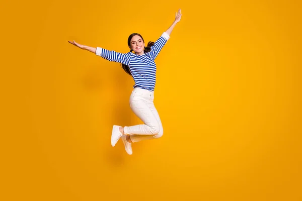 Foto em tamanho completo de menina alegre pular segurar a mão imagine que ela voar asas avião após descontos de primavera usar boa aparência roupas isoladas sobre fundo de cor brilhante — Fotografia de Stock