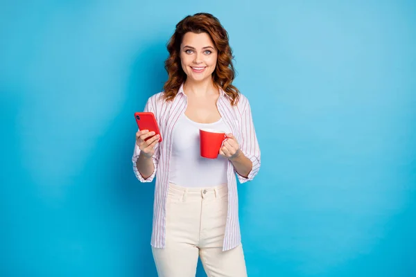 Портрет її красива приваблива красива весела хвиляста дівчина п'є чай з використанням пристрою додаток 5g вільний час ізольовано на яскравому яскравому сяйві яскравого синього кольору фону — стокове фото