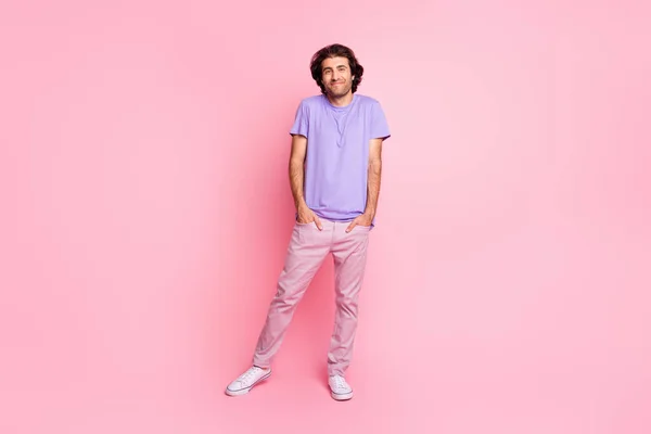 Foto de cuerpo entero de tímido tipo encogiéndose de hombros usar púrpura camisa pantalones zapatillas aisladas pastel rosa color fondo —  Fotos de Stock
