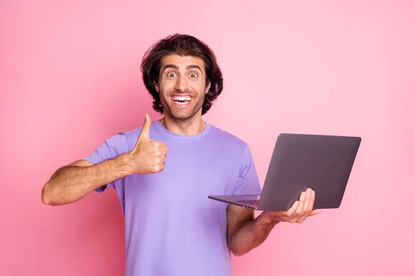 Фото божевільного фанк стильного модного коричневого волосатого чоловіка тримає комп'ютерне шоу великий палець вгору одягнути фіолетову футболку ізольовано на рожевому кольоровому фоні — стокове фото