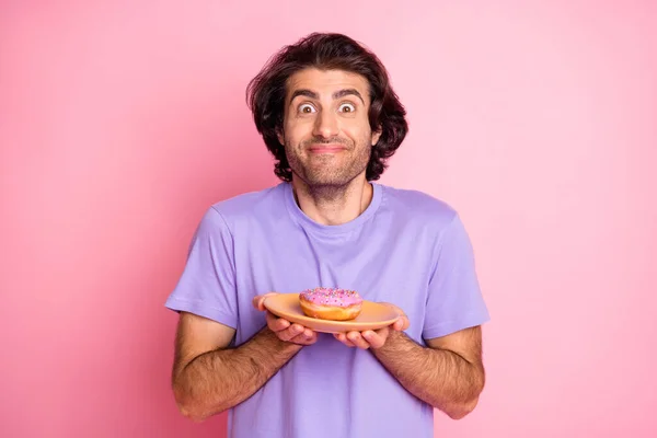 Photo excitée brun beau jeune homme tenir beignet sur plaque isolé sur fond de couleur rose brillant — Photo