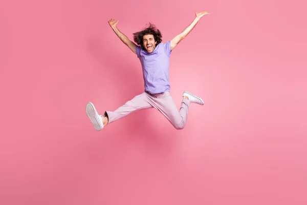 Full size foto van energieke jongeman verhogen handen springen in lucht succes dragen roze broek geïsoleerd op roze kleur achtergrond — Stockfoto