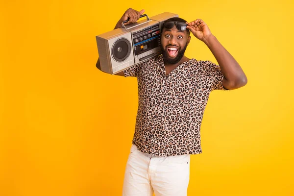 Foto de loco guapo de piel oscura chico mantenga hombro grabadora de cinta retro quitándose especificaciones frescas ver anuncio venta usar pantalones cortos leopardo camisa gafas de sol aislado vívido fondo amarillo —  Fotos de Stock