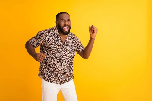 Foto av galen rolig mörk hud kille bra humör höja nävar firar framgång lotteri rik person bära gyllene halsband trend leopard skjorta vita shorts isolerad ljus gul bakgrund — Stockfoto