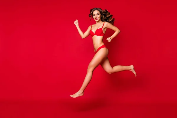 Teljes hossz testméret kilátás a szép vonzó karcsú vékony illeszkedés sportos csupasz láb vidám hullámos hajú lány ugrás futás cél kedvezmény elszigetelt fényes élénk ragyogás élénk piros háttér — Stock Fotó