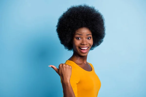 Foto porträtt av förvånad glad svart flådd flicka pekar med fingret på tomt utrymme leende isolerad på pulserande blå färg bakgrund — Stockfoto