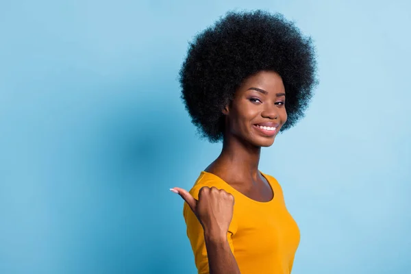 Retrato fotográfico de una chica de piel negra apuntando con el dedo al espacio en blanco sonriendo aislada sobre un vibrante fondo de color azul — Foto de Stock