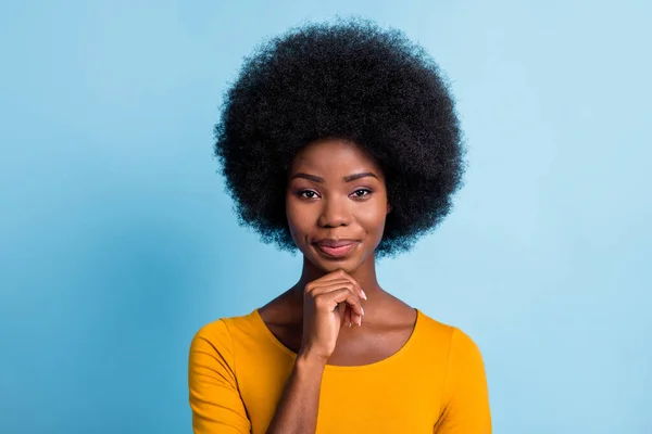 Foto av smart svart flicka volym frisyr titta kamera finger haka bära gul skjorta isolerad blå färg bakgrund — Stockfoto