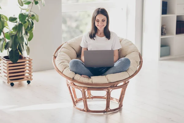 Foto de cuerpo completo de la chica positiva trabajo portátil sentarse silla de mimbre en el apartamento de la casa — Foto de Stock