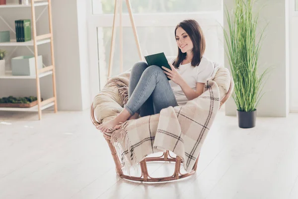 Foto de longitud completa de niña bonita sentarse silla de mimbre leer libro en la habitación de la casa moderna — Foto de Stock