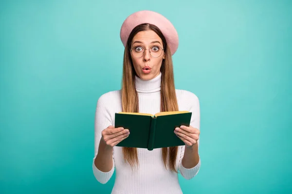 Photo of shocked lady hold love story book novel plot open mouth unexpected final ending wear specs modern pink beret cap white turtleneck isolated bright teal color background