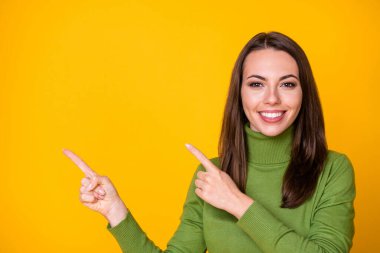 Close-up portrait of pretty confident cheerful girl pointing two forefingers aside copy space ad isolated bright yellow color background clipart