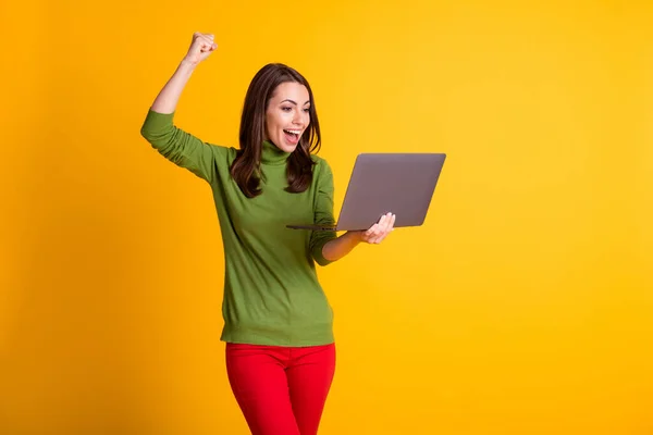 Foto di eccitata signora tenere notebook indossare maglione verde pantaloni rossi isolato colore giallo sfondo — Foto Stock