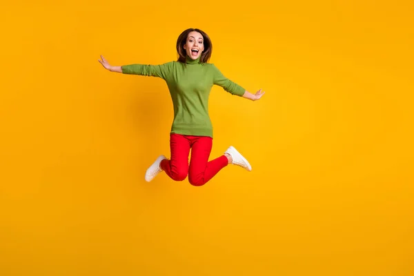 フルボディ写真の女性ジャンプアップ航空便喜び服カジュアルプルオーバースニーカー赤パンツ孤立した黄色の色の背景 — ストック写真
