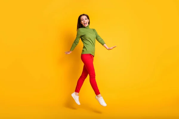 Full size profil zdjęcie śmieszne lady skakać spacery nosić zielone trampki pullover spodnie izolowane żółty kolor tło — Zdjęcie stockowe