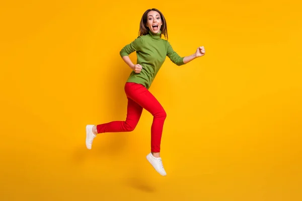 Foto de perfil de tamaño completo de la señora loca saltar a toda prisa desgaste casual zapatos de jersey verde pantalones rojos aislados de color amarillo fondo — Foto de Stock
